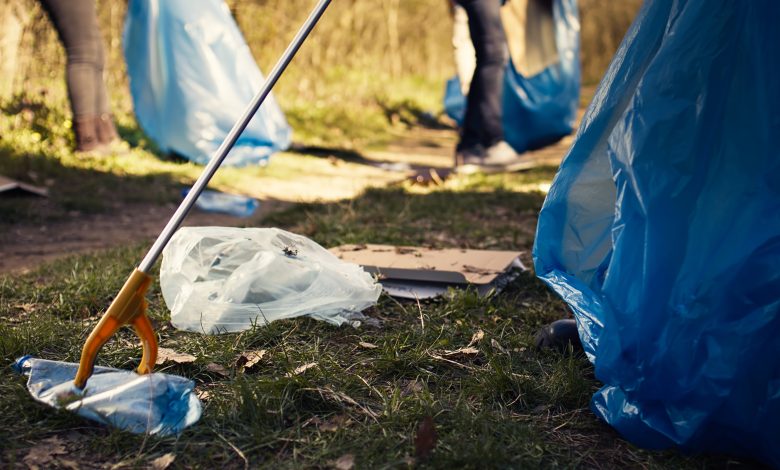 volunteer using tongs tool collect trash plastic waste from woods